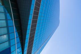 Low angle shot of the shiny, glass building, under the blue sky