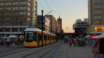 People and tram on the beautiful and colorful Alexanderplatz in Berlin, Germany, at colorful and beautiful sunset