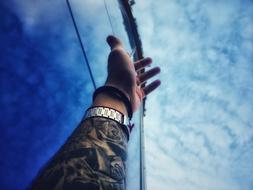 hand of man with tattoos on a background of blue sky
