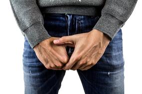 man in jeans holds hands at Testicles, Cancer awareness