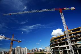 Cranes at the construction site under beautiful blue sky with white clouds