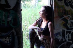 young Girl sits on doorway in grunge wall