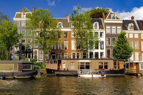 Beautiful and colorful cityscape of Amsterdam with the buildings on the shore and barges on the canal, in Netherlands