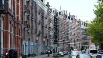 Beautiful street of Amsterdam, Netherlands, with the colorful buildings, cars, trees and people