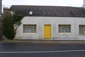 White cottage, with the yellow door, near the road in Ireland