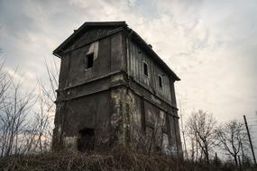 Old, abandoned railway building, among the trees, under the clouds