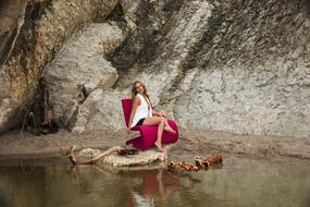 young woman posing on red chair at rock