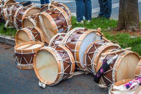 Brown wooden drums with sticks on pavement near the grass