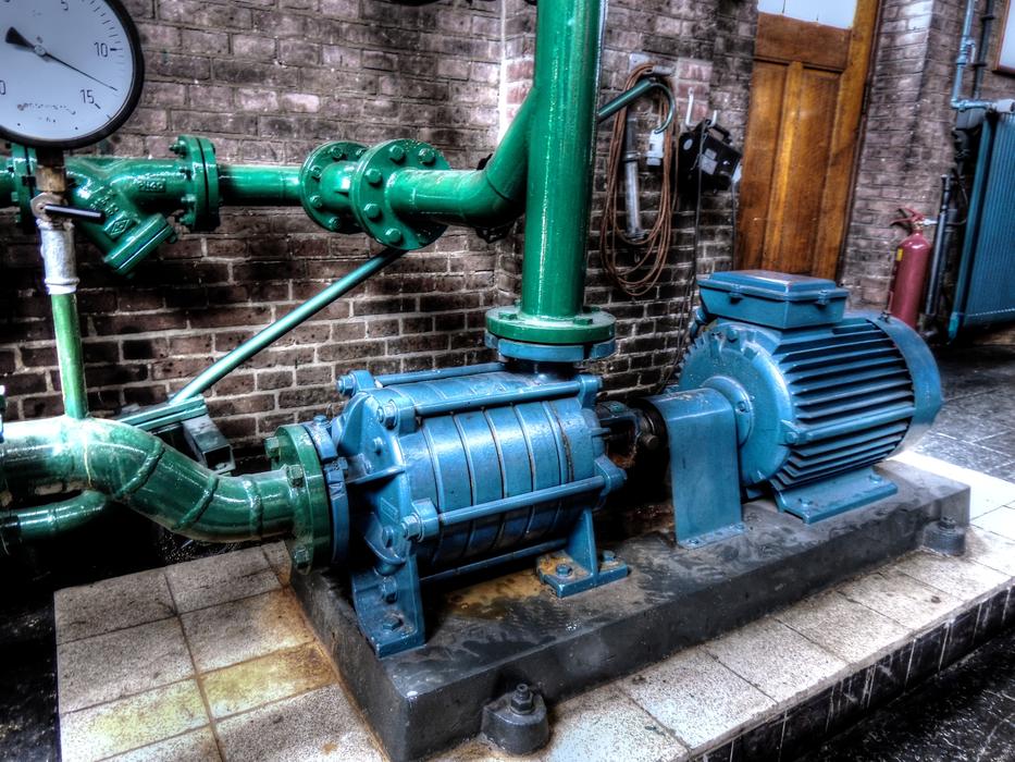 Shiny, colorful pump with pipes, near the wall
