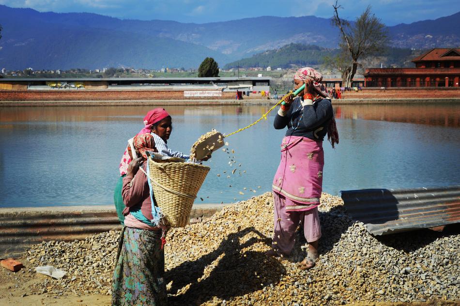 People working on the shore of the water, at background with mountains