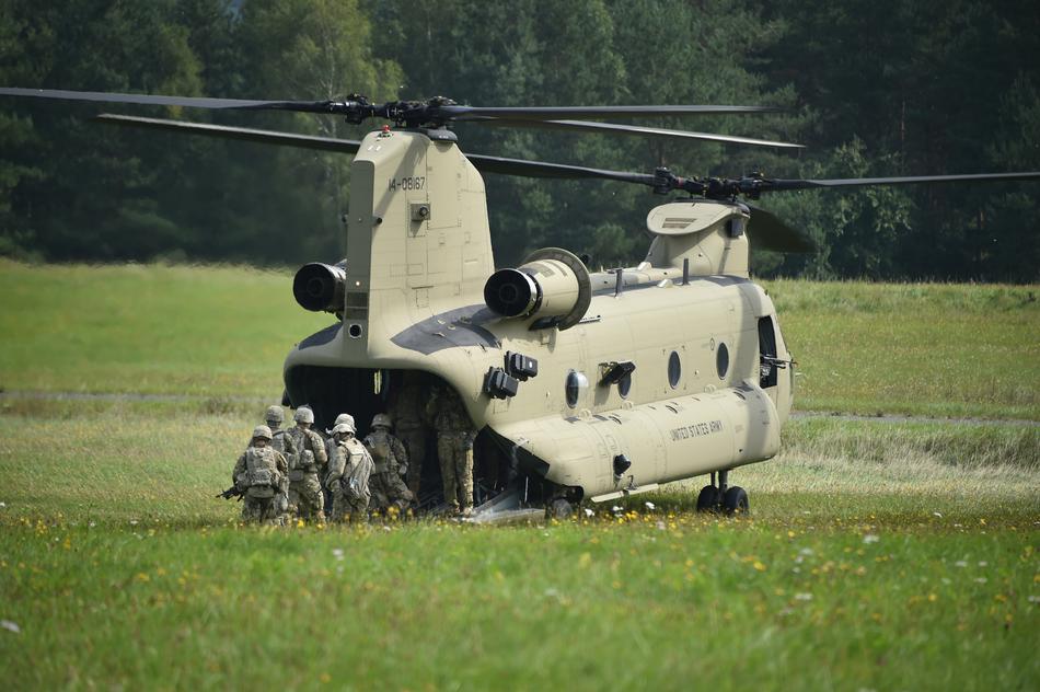Army Soldiers walking into the green helicopter on the green grass
