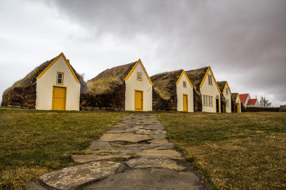 Beautiful farmhouses on the green field under cloudy sky in Iceland