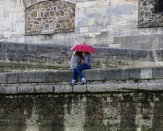 two friends are sitting under an umbrella on the promenade in Paris
