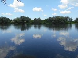 reflection of green trees and clouds in the river