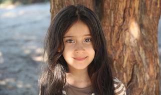 photo of a girl with long hair on a background of a brown tree trunk