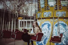 young girl sits on carousel in amusement park, russia, moscow