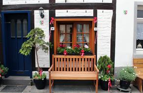 Beautiful, wooden garden bench, among the colorful plants, near the house in Germany