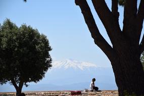 Girl near the green trees in Perpignan at beautiful snowy Pyrenees background in France