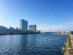 Beautiful shore of the river in Amsterdam, Netherlands, under the blue sky with clouds