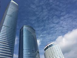 photo of three glass skyscrapers against a cloudy sky