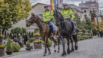 Police on the horses in the beautiful, old town with colorful plants