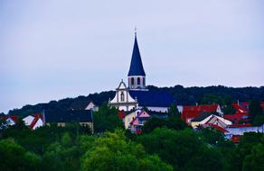 Spire on the roof of the house behind the trees