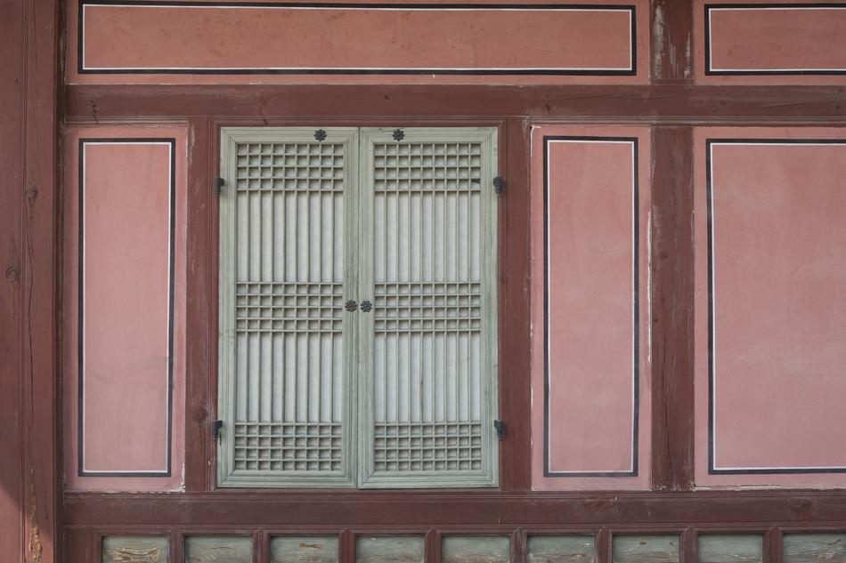 Window with white shutters, in the red and white brickwork house in Korea