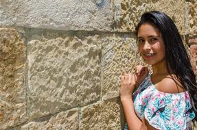 young brunette posing near a stone wall