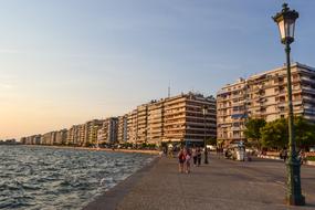 People, walking on the beautiful shore of Thessaloniki in Greece, at colorful sunset