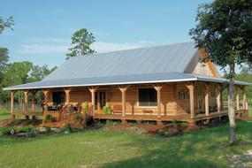 Beautiful log home, among the colorful plants in the country, at blue sky with clouds on background