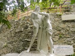 Beautiful sculpture of Adonis and Aphrodite, near the colorful trees and stone wall