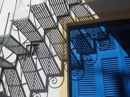 Stairs, with the shadow on the blue shutters, on the house in Greece