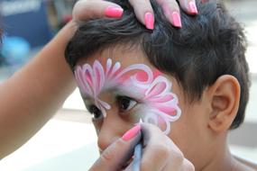 apply face painting to a child at the carnival