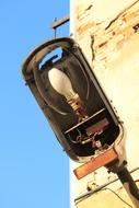 Close-up of the old light lamp with light bulb, on the wall, under the blue sky