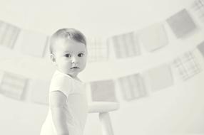 Black and white photo with the portrait of the cute baby, at background with the hanging clothes