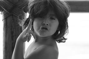 black and white photo of a boy with long hair on a blurred background