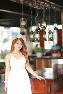 girl in white in a flower wreath posing in a cafe