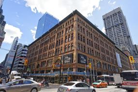 Cars, near the beautiful and colorful buildings in Toronto, Canada, under the blue sky with white clouds