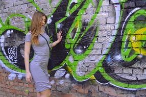 photo of a girl in a gray dress against a wall with graffiti