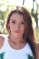 Portrait of the beautiful girl at blurred background with the plants in light