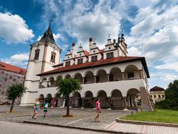 People, near the beautiful and colorful buildings in LevoÄa, Slovakia, among the green plants, under the blue sky with clouds