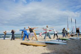 People, doing exercises on the sandy beach, in sunlight