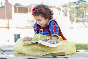 child girl wearing Disney Snow White costume reading book outdoor