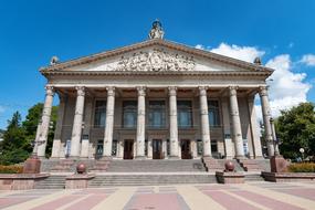 Beautiful and colorful theater, with the columns, in Ternopil, Ukraine, among the plants, under the blue sky with white clouds