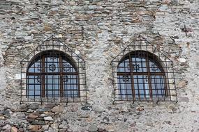 arched barred windows on the facade of a stone building