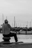 man with fishing rods in the harbor in black and white background