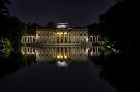 palace is reflected in the pond in Warsaw at night