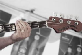 male hand with ring on neck of Bass guitar