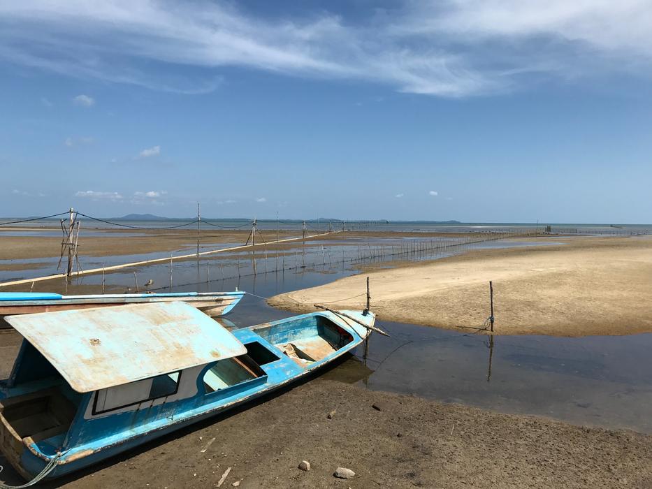 blue wooden boat on the beach by the sea