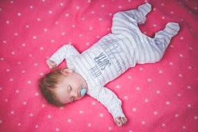 little child sleeping on a red blanket